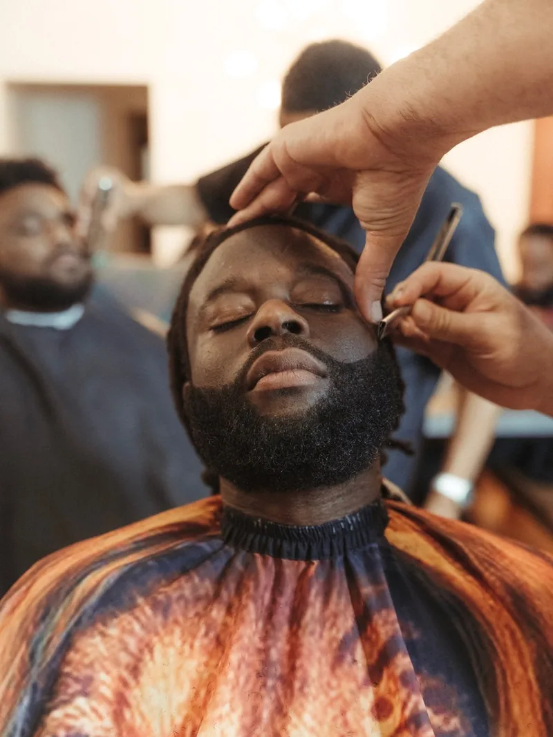 A man having his hairline edged by a barber at a retreat