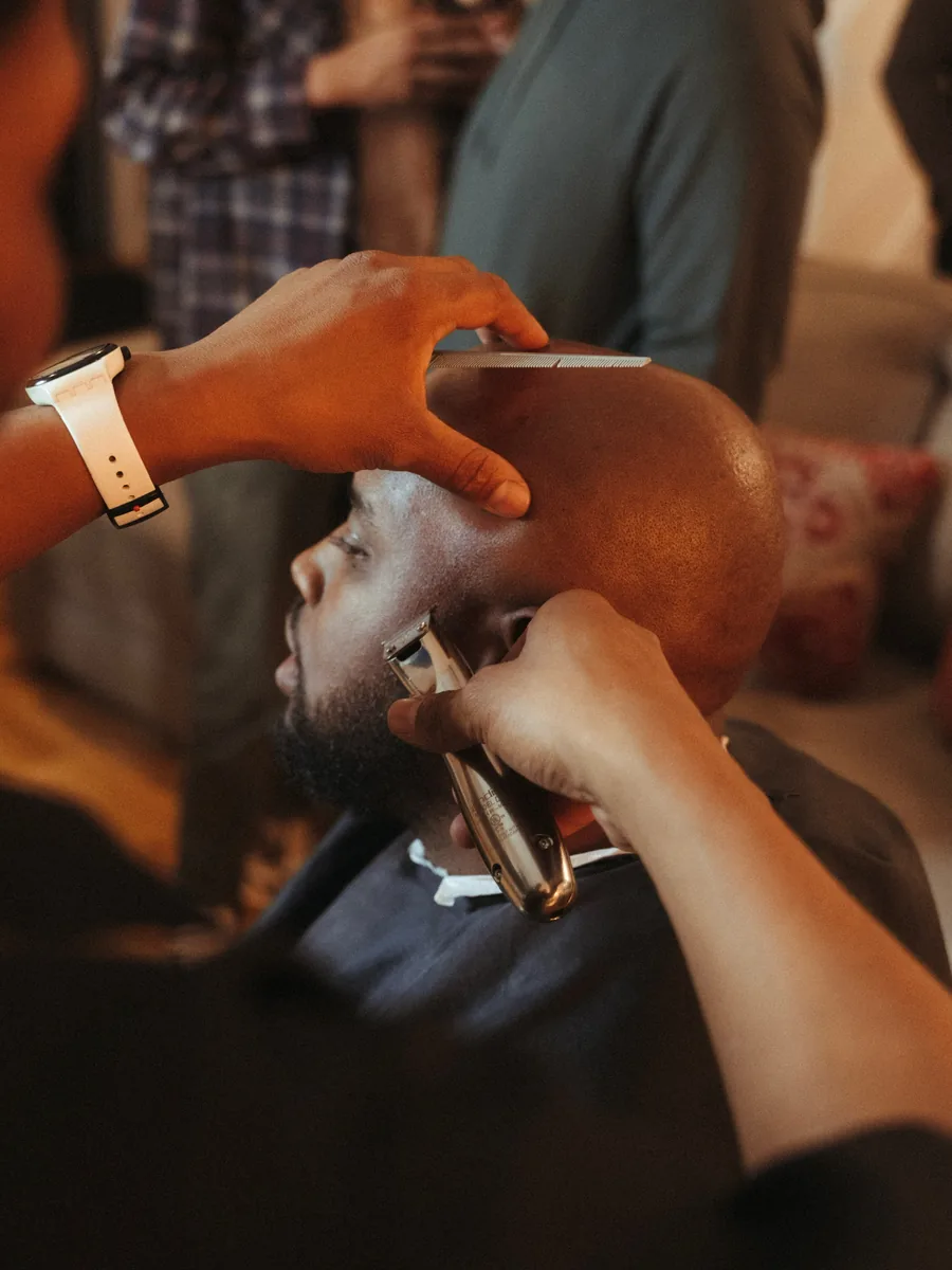 Close on a barber's hands working a straight razor along a man's jawline