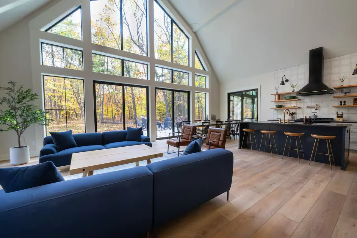 The open living room and kitchen inside The Gambrel with a double-height wall of windows