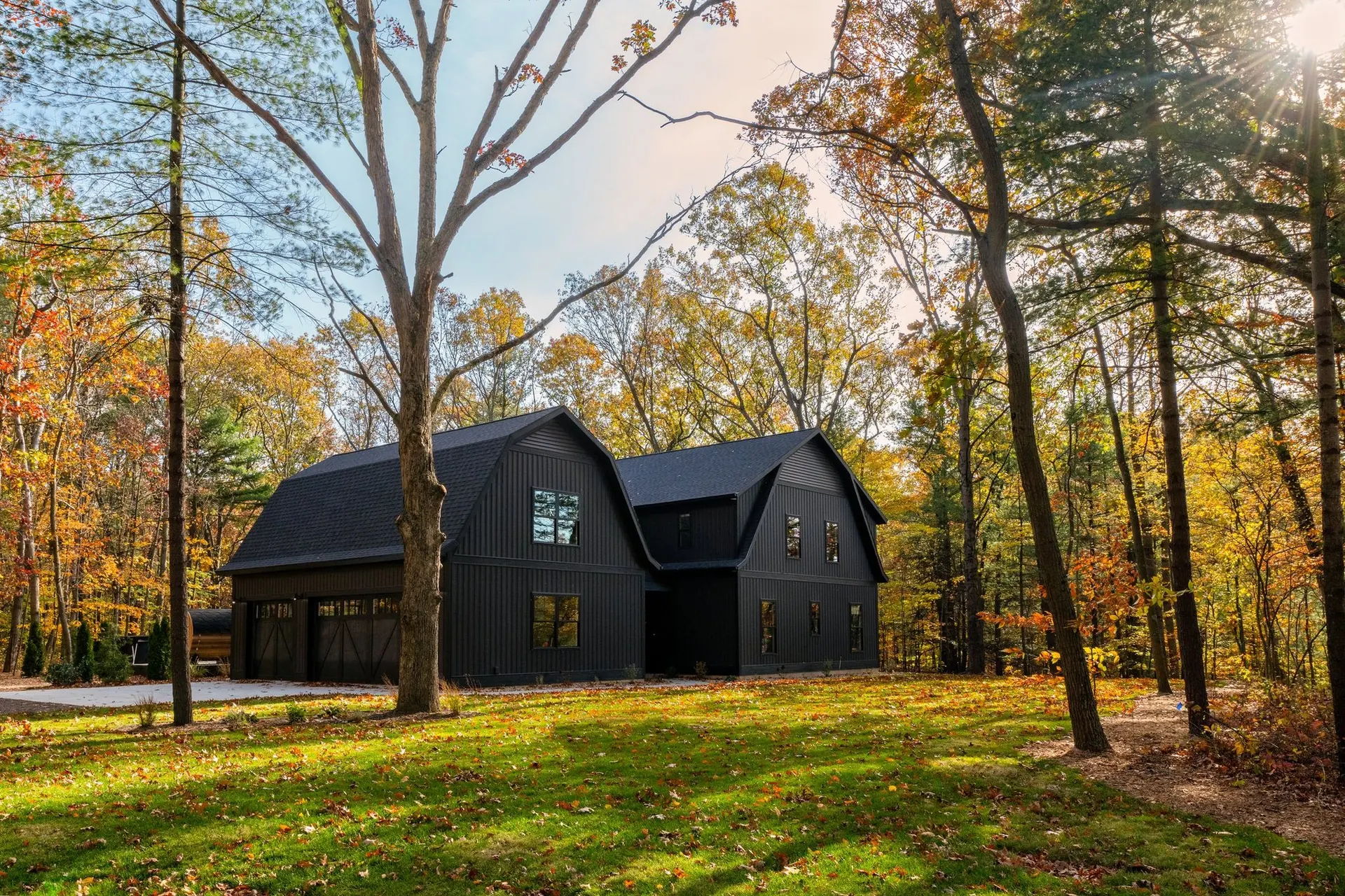The Gambrel at Black Barn Ridge, a black barn house among autumn trees in Saugatuck, Michigan