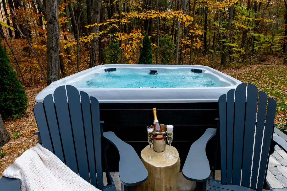 A hot tub set into a terrace with chairs beside it and autumn woods behind