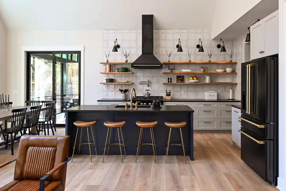 A long kitchen island with stools under pendant lights