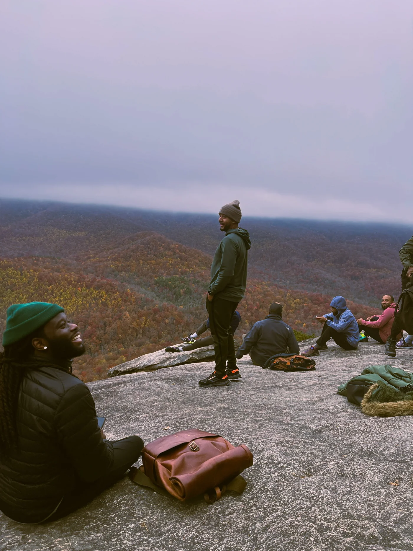 The men of The Healing resting on a granite overlook above autumn ridgelines